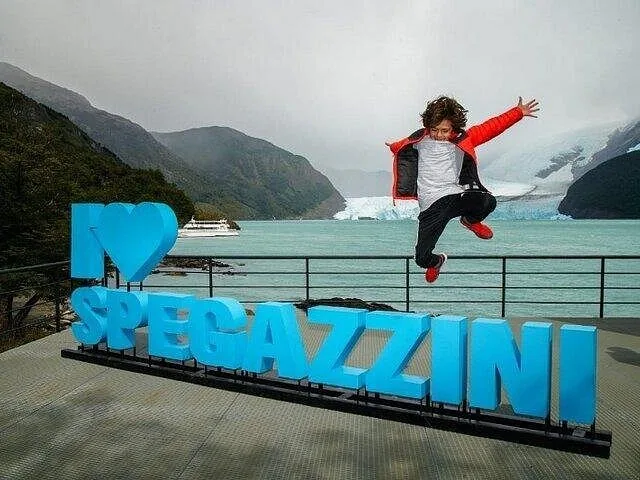 Un enfant saute joyeusement à côté d'un panneau « I Love Spegazzini ».