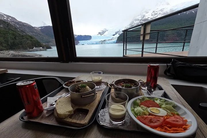 Un repas servi sur des plateaux avec une vue panoramique sur le glacier à l'extérieur.