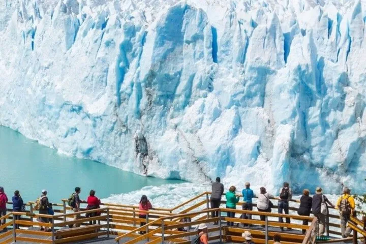 Des touristes se tiennent sur une plateforme d'observation et contemplent l'immense front du glacier Spegazzini.