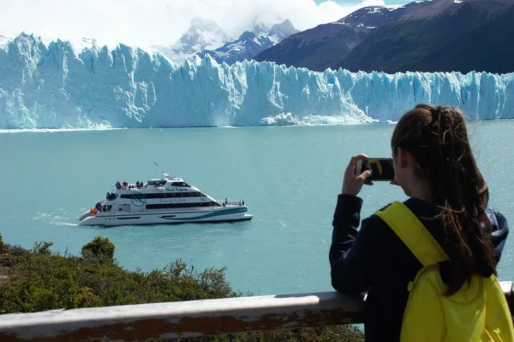 Een jong meisje maakt een foto van een tourboot bij de gletsjer.